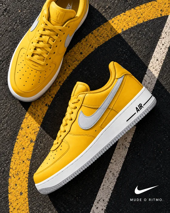Zapatillas Nike amarillas sobre el asfalto con la frase «Mude o ritmo.».